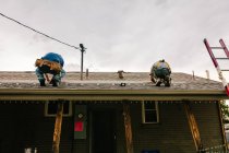 Two workmen installing solar panels on roof of house, low angle view — Stock Photo