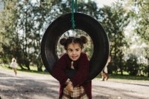 Young girl playing on tire swing — Stock Photo
