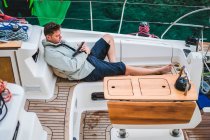 Чоловік, що відпочиває на яхті, дивиться на цифрову табличку (Хорватія). — стокове фото