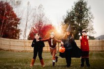 Портрет мальчика и девочки в костюмах на Хэллоуин в саду на закате — стоковое фото