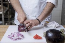Обрезанный вид повара, нарезающего красный лук — стоковое фото