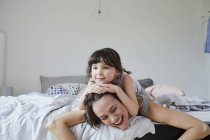 Mother and daughter lying on bed in light bedroom — Stock Photo