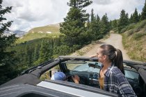 Jovem mulher olhando para fora de quatro rodas conversível em montanhas Rochosas, Breckenridge, Colorado, EUA — Fotografia de Stock