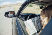 Blick über die Schulter einer im Auto sitzenden Frau mit Karte — Stockfoto