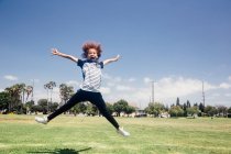 Écolière faisant le saut d'étoile sur le terrain de sport d'école — Photo de stock