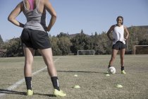 Duas jovens mulheres em campo de futebol jogando futebol — Fotografia de Stock