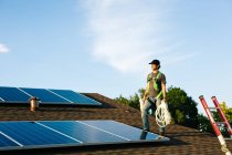 Arbeiter steht auf Hausdach und installiert Solarzellen — Stockfoto
