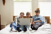 Female friends using laptop on bed — Stock Photo