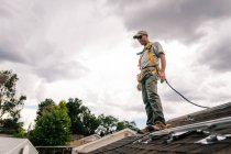 Workman no telhado da casa, preparando-se para instalar painéis solares, visão de baixo ângulo — Fotografia de Stock