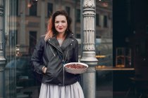 Portrait of woman in street holding dish of food — Stock Photo