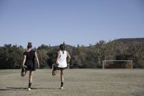 Mujeres estirando las piernas en el campo de fútbol - foto de stock