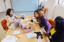 Колеги, які працюють разом за столом, діляться пончиками — стокове фото