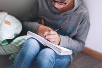 Девушка сидит на полу и пишет домашнее задание — стоковое фото