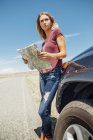 Женщина с картой на машине смотрит в сторону — стоковое фото