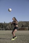 Mujer joven en campo de fútbol con fútbol - foto de stock