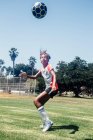 Studentessa adolescente testa pallone da calcio sul campo sportivo della scuola — Foto stock