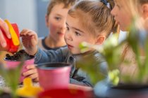 Mid adult woman helping young children with gardening activity, close-up — Stock Photo