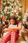 Portrait of girl with dog unwrapping Christmas gift — Stock Photo