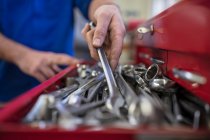 Mains de mécanicien de voiture mâle sélectionnant la clé de la boîte à outils dans le garage de réparation — Photo de stock