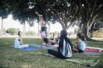 Colegialas practicando yoga handstand en el campo de deportes escolares - foto de stock