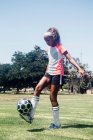 Школярка-підліток практикує тривалий час з футбольним м'ячем на шкільному спортивному полі — стокове фото