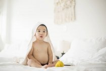 Маленький мальчик с белым полотенцем в капюшоне в постели — стоковое фото