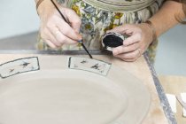 Жіночі руки малюють на глиняній тарілці — стокове фото