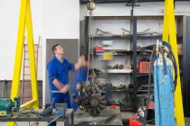 Männlicher Automechaniker hebt Auto-Motor in Werkstatt — Stockfoto