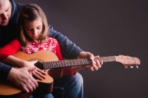 Отец учит дочь играть на гитаре — стоковое фото