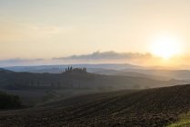 Rolling backlit landscape at sunset, Tuscany, Italy — Stock Photo