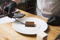 Cropped view of chef placing cake on plate — Stock Photo