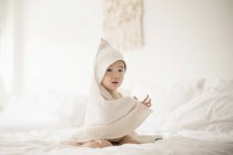 Menino com toalha com capuz na cama — Fotografia de Stock