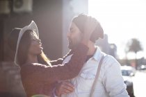 Женщина надевает вязаную шляпу на мужчину на открытом воздухе — стоковое фото