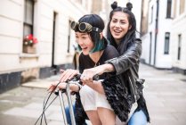 Two young stylish women cycling on retro bicycle — Stock Photo