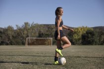 Jovem mulher em campo de futebol jogando futebol — Fotografia de Stock