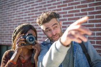Man and woman outdoors, man pointing ahead, woman looking through camera — Stock Photo