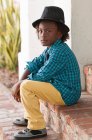 Портрет мальчика в фетровой шляпе, сидящего на улице — стоковое фото