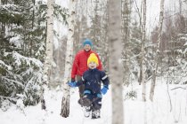 Hombre e hijo caminando en el bosque cubierto de nieve - foto de stock