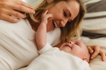 Woman on bed playing with baby daughter — Stock Photo