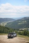 Road trip couple looking out at mountains from off road vehicle hood, Breckenridge, Colorado, USA — Stock Photo