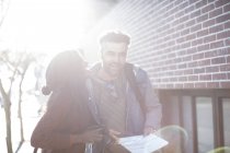 Мужчина и женщина с картой и камерой смеются на улице — стоковое фото