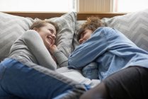 Two female friends smiling to each other on bed — Stock Photo
