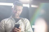 Взрослый мужчина улыбается и пользуется смартфоном — стоковое фото