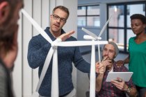 Cidade do Cabo, África do Sul, colegas juntos no escritório olhando para o modelo de turbina eólica — Fotografia de Stock