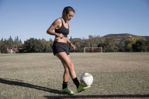 Mujer en campo de fútbol jugando fútbol - foto de stock