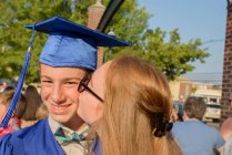 Fille embrasser garçon sur la joue à la cérémonie de graduation — Photo de stock