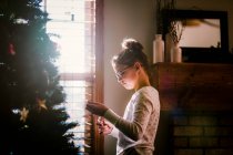 Vista lateral de chica decorando árbol de Navidad - foto de stock