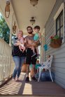 Famille devant le porche de la maison — Photo de stock