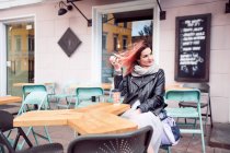 Femme assise à table au café pavé — Photo de stock