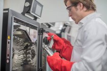Мужчина, работающий на заводе по производству ниток, берет стаканы из химической печи — стоковое фото